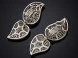 three silver pendants with black diamonds on a black background
