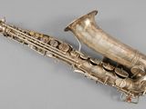 an old silver saxophone sitting on top of a gray surface