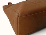 brown leather handbag on a white background with a blue tag