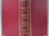 an old red book with gold trim sitting on top of a white surface