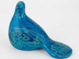 une figurine d'oiseau bleu posée sur une surface blanche
