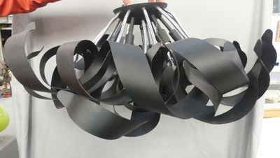 une personne tenant un lustre noir fabriqué à partir de bandes de métal