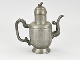an antique silver teapot with a bird on the handle