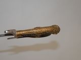 a small knife with a gold handle on a white surface