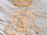 an image of a bed with a white comforter with a floral design on it
