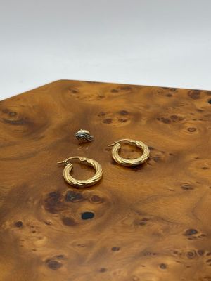deux paires de boucles d'oreilles créoles en or posées sur une table en bois