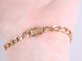 gold plated bracelet with a padlock clasp on a woman ' s wrist