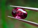 un gros plan d'un diamant rose tenu par une paire de pinces