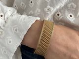 a close up of a woman ' s hand wearing a gold bracelet