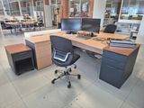 a desk with two computers and a chair in the middle of the room