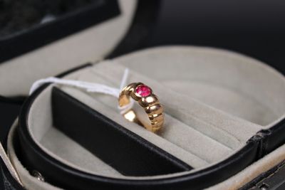 une bague en or sertie d'une pierre rose, dans un écrin
