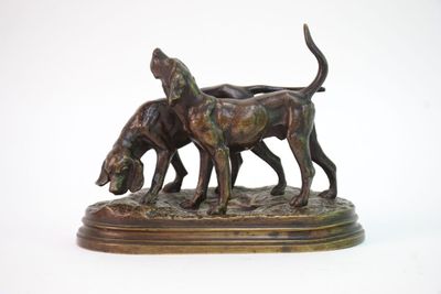 statue en bronze représentant deux chiens sur un socle, sur fond blanc