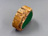 an image of a gold and green ring on a gray surface