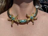 the woman is wearing a gold necklace with turquoise beads and starfishs