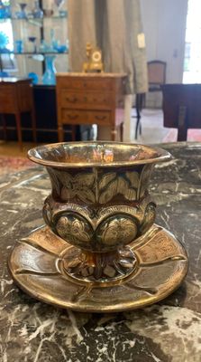 une tasse et une soucoupe en or posées sur une table en marbre
