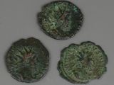 trois pièces de monnaie romaines anciennes posées sur une surface blanche