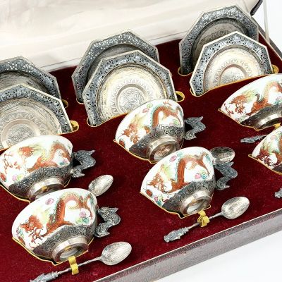 six tasses et soucoupes dans une boîte avec des cuillères