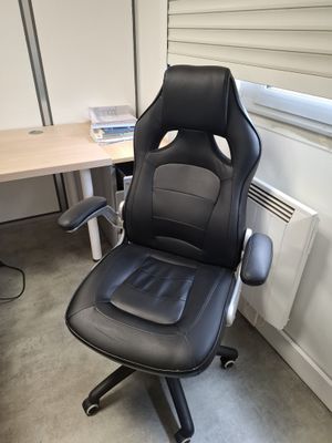 a black office chair sitting in front of a computer desk