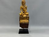 une statue en or représentant un Bouddha assis, posée sur un socle en bois
