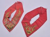 two pieces of red fabric with gold embroidery on them on a white surface