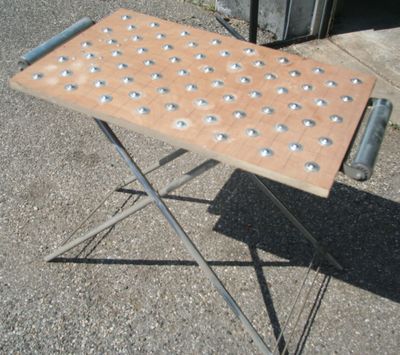 une petite table percée de trous, posée sur le trottoir