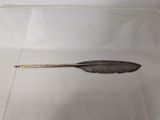 a silver feather on a stick in a white box
