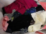 a basket full of clothes that is sitting on a bed