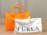 an orange purse and a white bag sitting on a table
