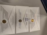 three envelopes with a gold coin on top of them on a table