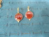 pair of red and gold earrings on a blue cloth