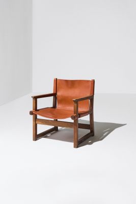 un fauteuil en cuir marron posé sur un sol blanc
