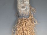 une image représentant un masque en bois sur lequel poussent des racines