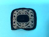 a black and silver brooch on a blue surface