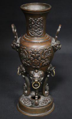 a bronze vase with a lion on it on a black background