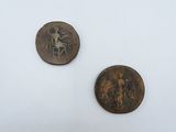 two old coins are sitting on a white surface, one of which has a picture of a man on a horse