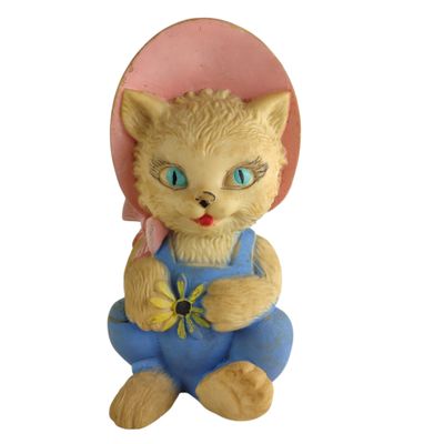 une figurine représentant un chat avec un chapeau rose et une salopette bleue