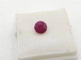 a close up of a red ruby stone on a white surface