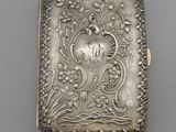 un étui à cigarettes ancien en argent, orné d'un motif représentant un oiseau et des fleurs