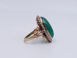 a close up of a ring with a green stone in it