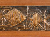 a wooden plaque with a fish design on it