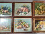 quatre tableaux encadrés représentant des fruits et des fleurs, accrochés au mur d'une pièce