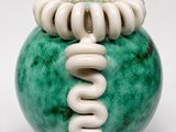 a green and white vase with a spiral design on it