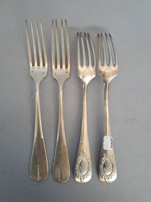 four forks and a knife are lined up on a table