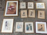 many framed pictures on the floor next to a basket of flowers