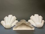 three white shell shaped vases sitting on top of a table