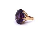 a close up of a ring with a purple stone on a white background