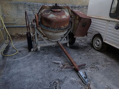 une bétonnière garée à côté d'une remorque dans une cour