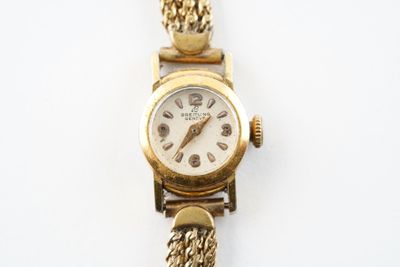 une montre en or entourée d'une chaîne sur une surface blanche