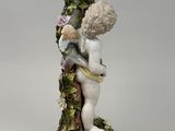 a figurine of a boy holding a bird on top of a tree