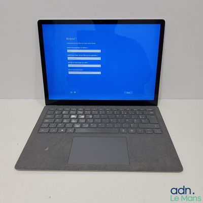 un ordinateur portable ouvert posé sur une table blanche